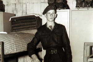 Soldaat Van Dam in uniform bij zijn bed en kast